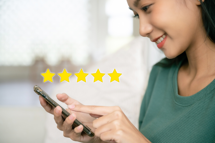 Smiling woman holding a phone showing five gold stars